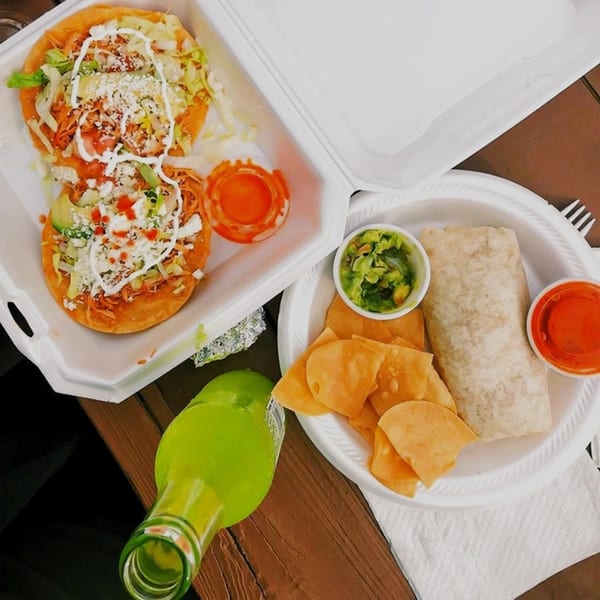 El Oasis Mexican food: two tostadas, a burrito, chips, guacamole, salsa, and a green soda.