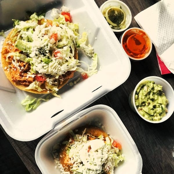 Two El Oasis Mexican tostadas with shredded chicken, lettuce, cheese, and salsa, with guacamole.